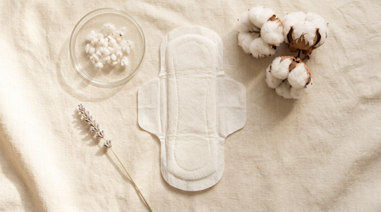 Organic cotton period pad flat lay with cotton bolls on cream linen